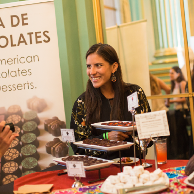 A representative from Casa de Chocolates presenting artisanal Mexican desserts at a tasting station.